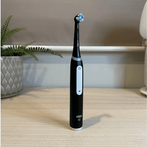 The Oral-B iO Series 3 electric toothbrush in black, a great value model, standing on a desk.