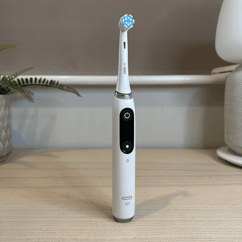 White Oral-B iO Series 8 electric toothbrush with its interactive display, standing alone on a desk.